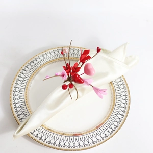 Detail of red and pink heart napkin ring with berries on white satin napkin