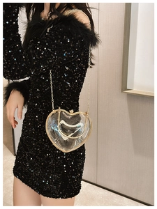 Detail of transparent heart-shaped acrylic crossbody bag with gold chain strap on model