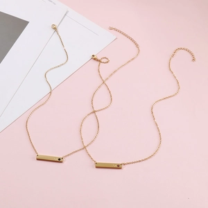 Detail of two gold bar necklaces with embedded small pink and black birthstones