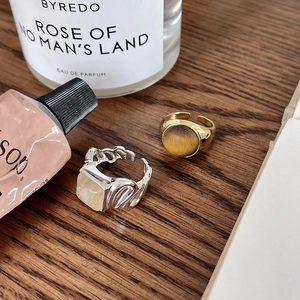 Detailed shot of gold tiger eye ring and textured silver ring on a dark wooden table