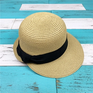 Dettaglio di un cappello di paglia a tesa larga con fiocco nero su un pavimento di legno