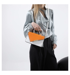 Close-up of orange and white leather handbag with silver round metal handle and strap