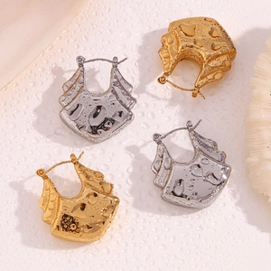 Detail showing gold and silver hollow wave earrings on a textured water-drop background