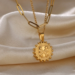 Detail of gold sunflower pendant with double arrow relief on textured silk background