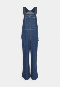 Close-up of deep blue denim fabric texture and stitching on casual loose overalls