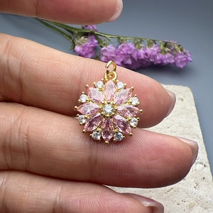 Exquisite gold floral pendant with pink and white zircon stones held in hand