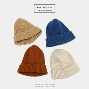 Flat lay of knit beanies in khaki, navy, caramel brown, and off-white colors