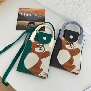 Detail of knitted mini phone bags in green and black with bear patterns and strap