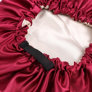 Detail view of burgundy satin sleep bonnet with adjustable buckle and cream lining