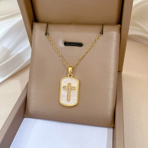 Macro view of gold titanium cross pendant with shell inlay and diamonds in jewelry box