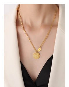 Close-up of gold double-layer OT buckle necklace with letter engraved round pendant on model