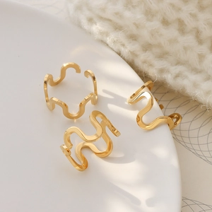 Three gold U-shaped wavy open rings in stainless steel on a white decorative plate