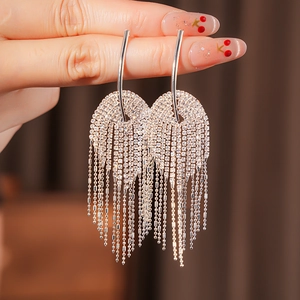 Gros plan de boucles d'oreilles pompon argentées avec strass brillants et chaînettes