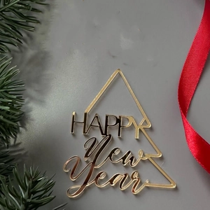 Close-up of golden acrylic Christmas tree cake topper with Happy New Year text design