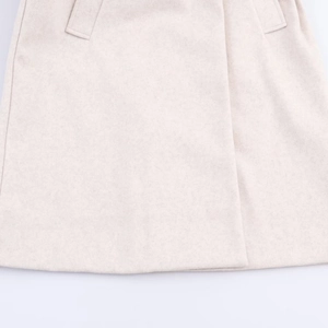 Close-up of heavy beige wool fabric texture and pocket detail on a hooded winter coat