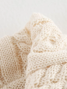 Close-up of cable knit texture on cream-colored long sleeve knitwear and skirt set