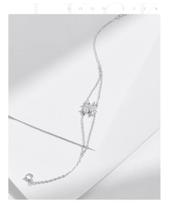 Detailed view of silver clover bracelet with heart-shaped crystals and lucky phrase