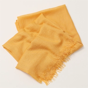 Close-up of yellow cotton linen scarf showing fabric texture and tassel fringe details