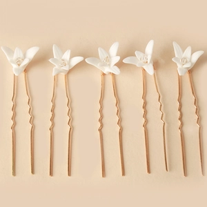 Detail of 5-piece bridal U-shaped hair pins with white ceramic flowers and gold crystals