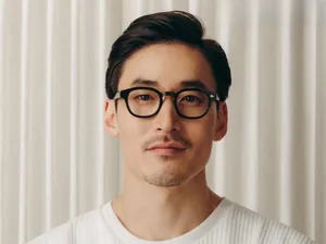 Gros plan de lunettes rondes rétro noires avec rivets argentés portées par un homme