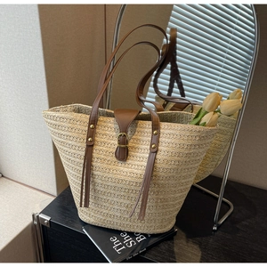 Detail of beige straw tote bag with brown leather straps and fresh tulips inside
