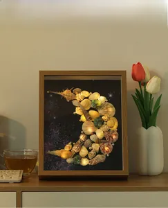 Close-up of DIY shell art light frame with crescent moon design and warm LED lights