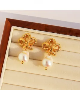 Detail of gold twisted knot earrings with Baroque pearl charms in a velvet box