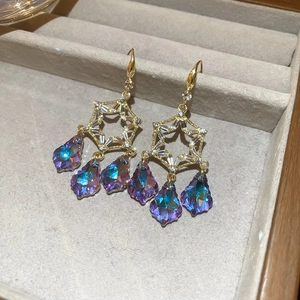 Detailed macro view of gold leaf earrings with iridescent crystal drops and zircons