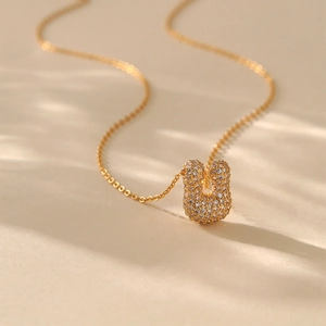 Macro view of gold horseshoe necklace pendant featuring shimmering cubic zirconia pavé