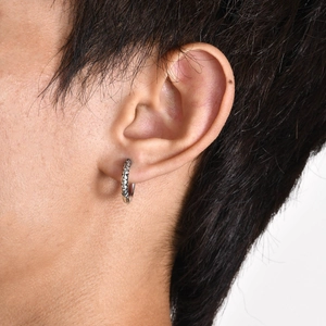 Vintage silver hoop earrings with intricate floral daisy pattern on a female model