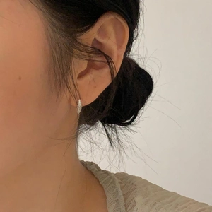 Close-up of minimalist sterling silver round hoop earring with zircon on an ear