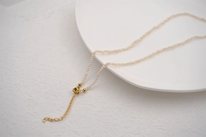 Close-up of elegant mini white seed pearls with gold clasp on a ceramic plate
