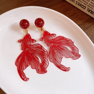 Vue macro des boucles d'oreilles poisson rouge évidées rouges sur porcelaine blanche