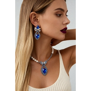 Detail of luxury teardrop blue crystal necklace and bow pearl earrings on model