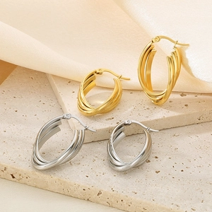 Detail of layered gold and silver U-shaped titanium steel hoop earrings on silk background