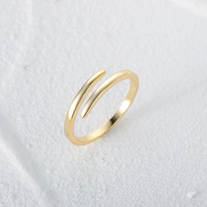 Macro shot of minimalist s925 silver cross ring with gold finish and open teardrop design