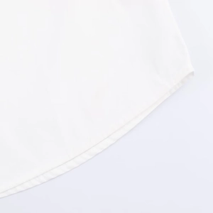 Detailed view of curved hem and stitching on white poplin shirt with fine needlework