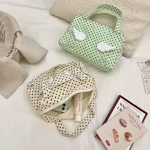 Polka dot canvas toiletry bags with plush wings decoration shown in cream and mint green