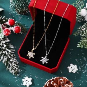 Close-up of gold and silver snowflake necklaces with zircons in a red gift box
