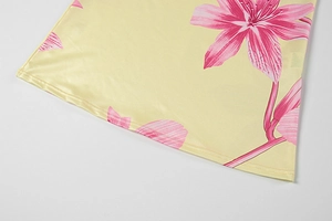 Detailed macro view of yellow silk fabric featuring elegant pink lily floral patterns