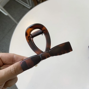 Detail of amber tortoiseshell hair claw clip with twisted knot design and metal spring
