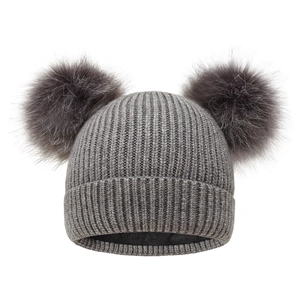 Close-up of the chunky knit texture and soft double faux fur pom-poms on the grey winter beanie