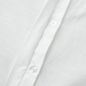Detailed macro view of the natural linen texture and white buttons on this summer dress