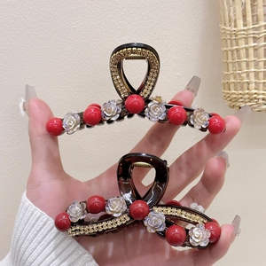 Close-up of elegant camellia hair claw clip with ivory flowers and red beads decor