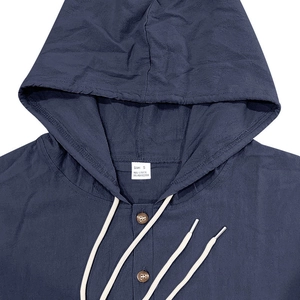 Detail of hooded linen shirt neckline with adjustable drawstrings and button closure