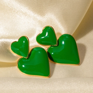 Dettaglio di orecchini a doppio cuore verde placcati in oro su seta lussuosa
