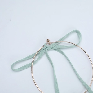 Détail d'un anneau métallique doré avec un ruban en tricot vert clair pour décoration