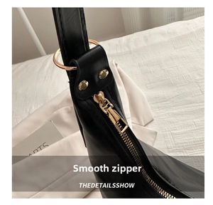 Close-up of smooth gold metal zipper and stitching detail on a black PU leather handbag