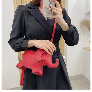 Detail view of red leather elephant shaped crossbody bag with thin strap on model