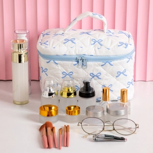 Quilted white cosmetic bag with blue bow prints and light blue handle for travel